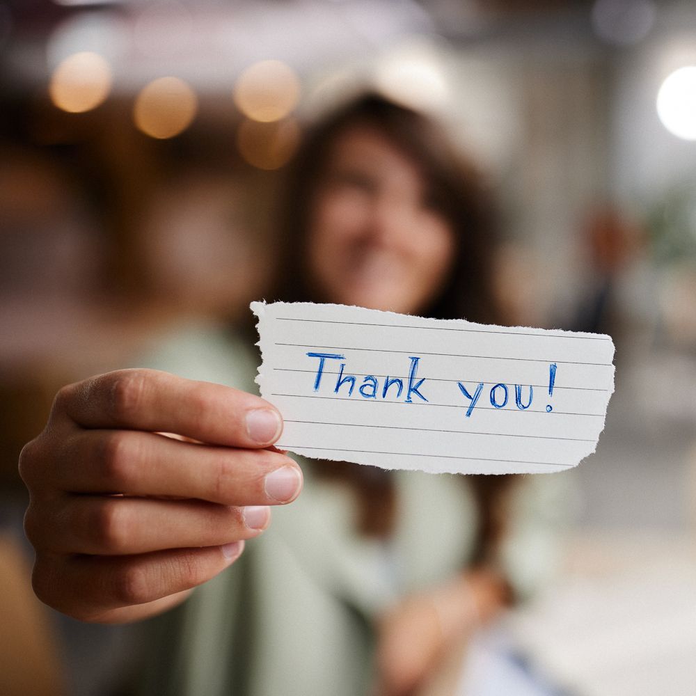 Someone holding up a thank you card.